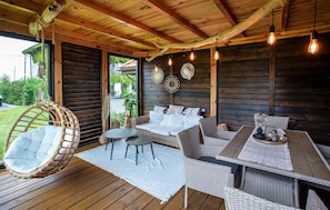 A wooden deck with wicker furniture, including a hanging chair and a sofa set. - Gorgeous apartment in Nowecin with WiFi (Nowecin)