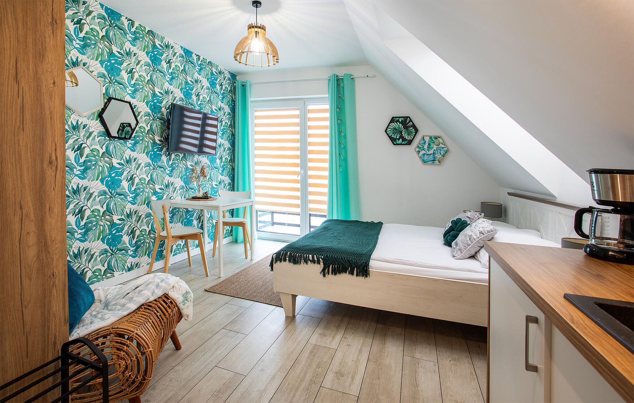 A bedroom with a bed, a desk, a chair, a television, and a coffee maker.