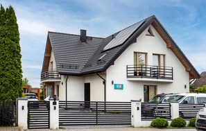 A two-story house with a sloped roof, a balcony on the upper floor, and a gated driveway. - Gorgeous apartment in Nowecin with WiFi (Nowecin)
