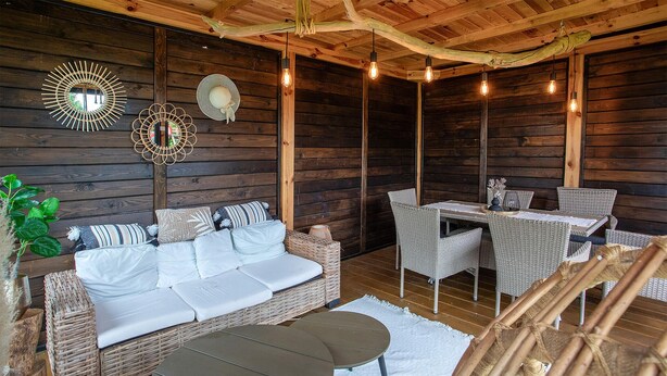 A cozy wooden cabin interior with a sofa, wicker chairs, a dining table, and hanging light fixtures. - Gorgeous apartment in Nowecin with WiFi (Nowecin)