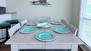 Una mesa de comedor con seis sillas, cada una con un plato color turquesa.