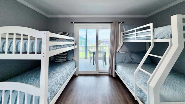 Una habitación con literas, una lámpara en el techo y vistas a través de un ventanal.
