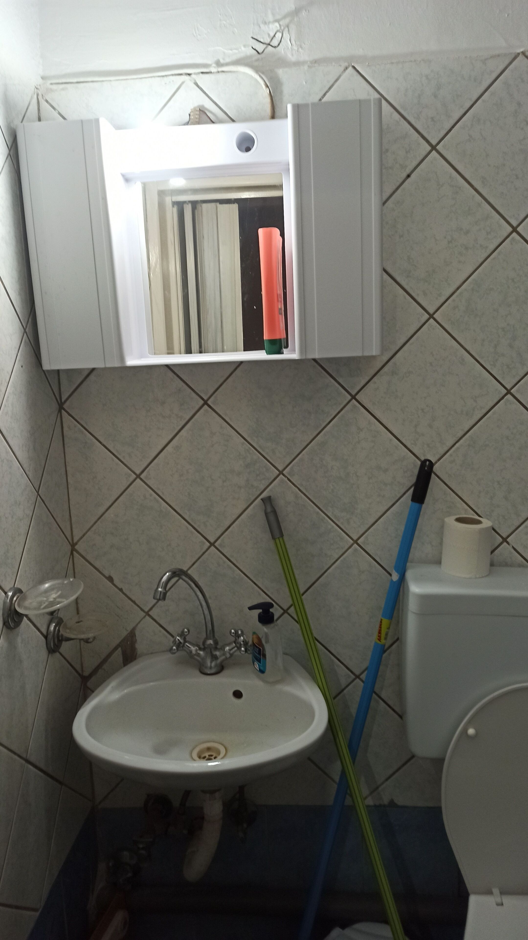 A bathroom with a sink, toilet, and a mirror above the sink.