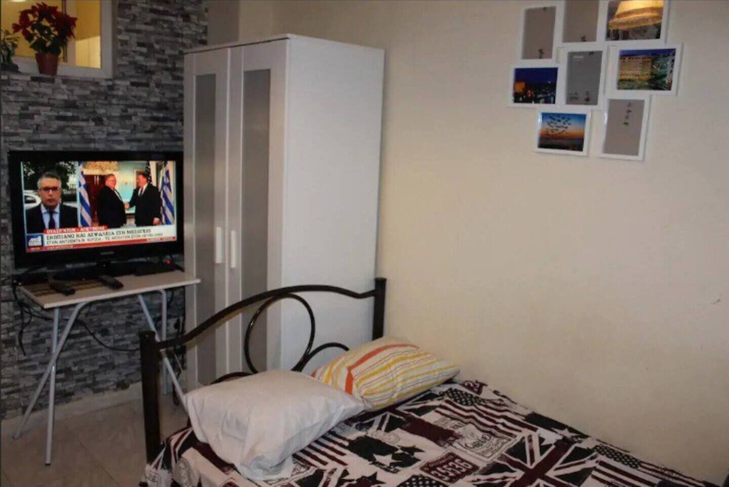 A bedroom with a bed, a television on a stand, a wardrobe, and a wall with pictures.
