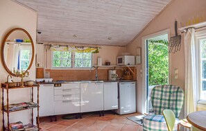 A compact kitchen with white cabinets, a microwave, and a sink. There's a window with a view of greenery outside. - Stunning home in Borrby (Borrby)