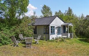 A small wooden house with a porch, surrounded by greenery and outdoor furniture. - Stunning home in Borrby (Borrby)
