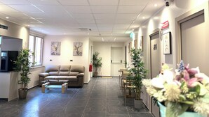 A reception area with a sofa, chairs, a coffee table, and potted plants. - Hotel Lume (Milano)