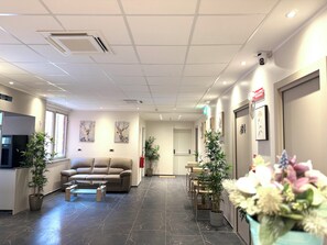 Aula, jossa on sohva, tuoleja, sohvapöytä ja ruukkukasveja.