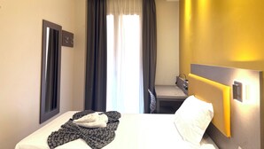 A hotel room with a bed, a desk, and a window with curtains. - Hotel Lume (Milano)