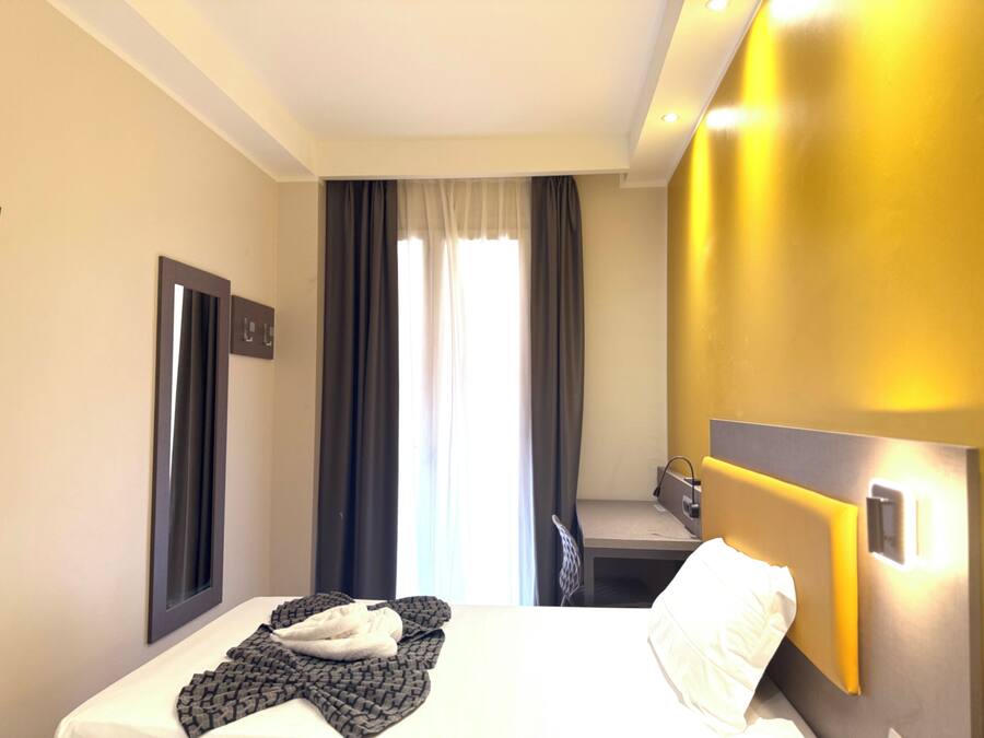 A hotel room with a bed, a desk, and a window with curtains.