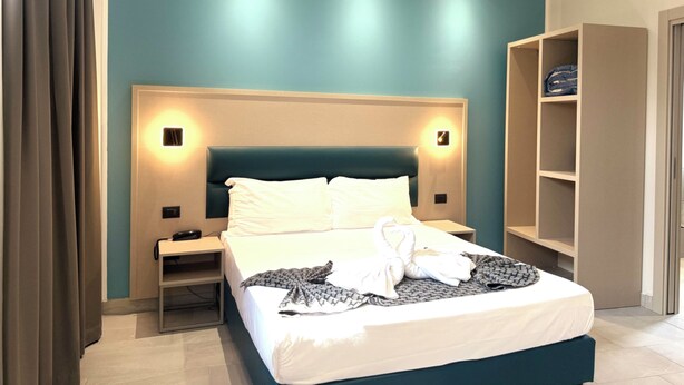 A hotel room with a bed, bedside tables, a wardrobe, and a wall-mounted light fixture. - Hotel Lume (Milano)