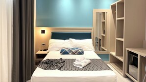 A hotel room with a bed, a bedside table, a lamp, a wardrobe, and a mirror. - Hotel Lume (Milano)