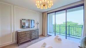 Ein Hotelzimmer mit einem großen Bett, einem Schminktisch, einem Spiegel und einem Balkon mit Aussicht.
