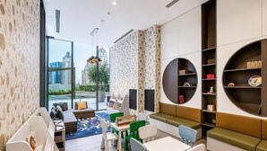 A modern children's play area with seating, tables, and storage units. - Luxury 2BR Plus Maids, High-Floor Marina Views (Dubai)