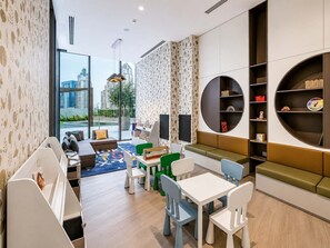 A modern children's play area with seating, tables, and storage units. - Luxury 2BR Plus Maids, High-Floor Marina Views (Dubai)