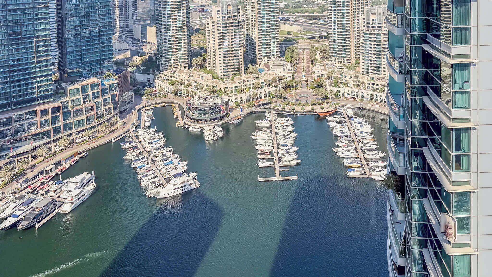 A marina with boats docked, surrounded by high-rise buildings.