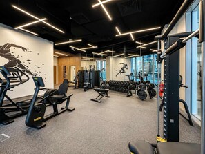 A gym with exercise equipment, a wall with a dynamic design, and large windows. - Luxury 2BR Plus Maids, High-Floor Marina Views (Dubai)
