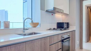 A modern kitchen with a stainless steel sink, a gas stove, and an oven. - Luxury 2BR Plus Maids, High-Floor Marina Views (Dubai)