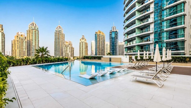 A rooftop swimming pool with lounge chairs and umbrellas, surrounded by high-rise buildings. - Luxury 2BR Plus Maids, High-Floor Marina Views (Dubai)