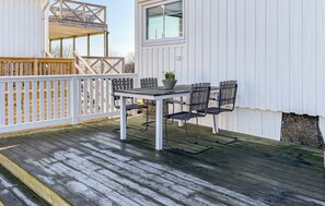 A covered outdoor area with a table and chairs, a potted plant, and a white railing. - Cozy home in Varberg with house sea view (Varberg)