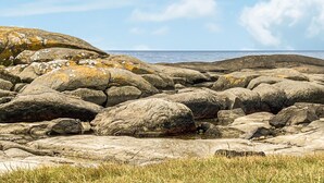 En stenet kystlinje med store sten og et lille vandareal.