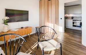 A modern kitchen with stainless steel appliances, a wooden dining area with a table and chairs, and a large abstract painting on the wall. - Cozy home in Varberg with house sea view (Varberg)