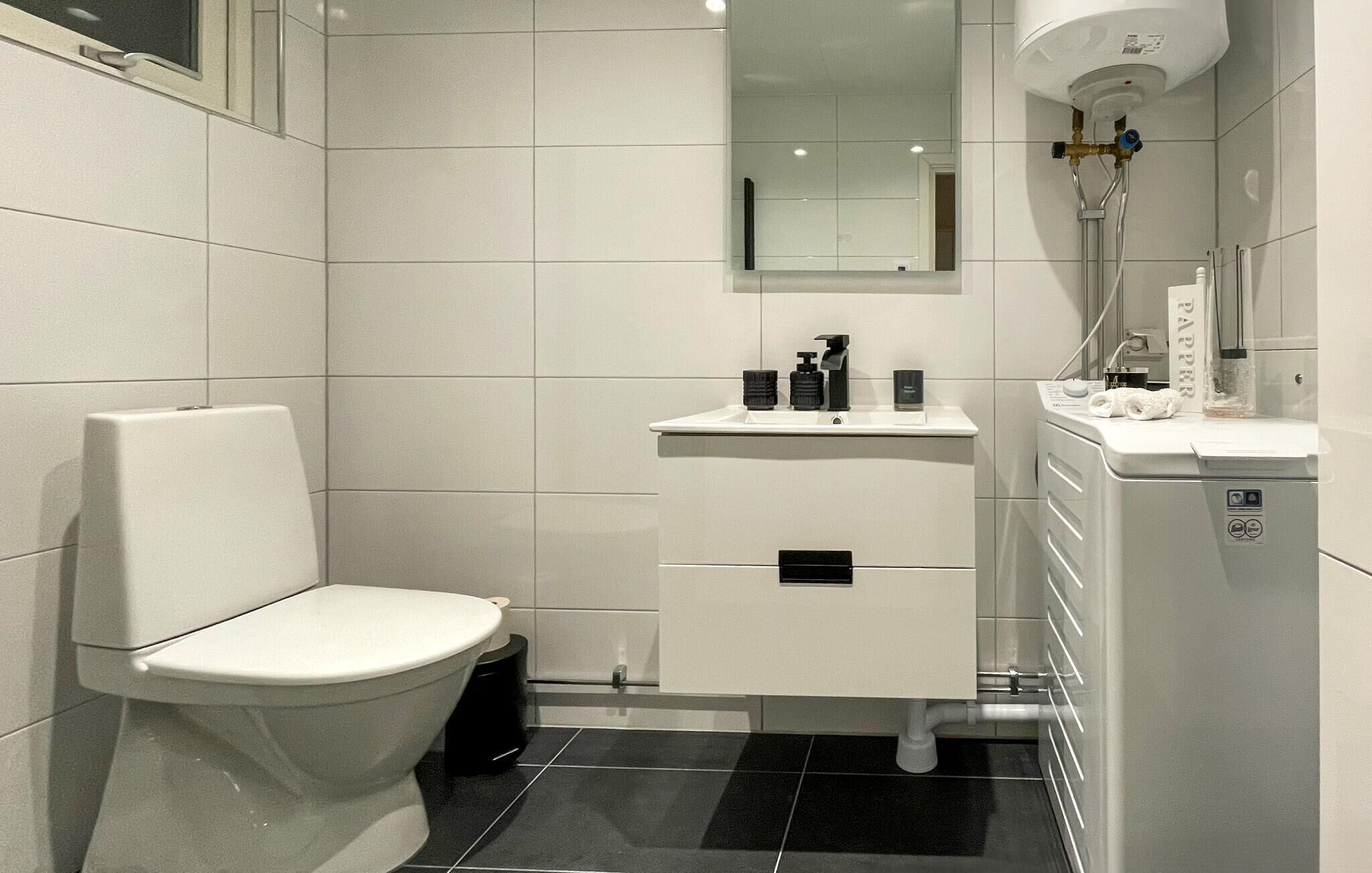 Une salle de bain moderne équipée d’un WC, d’un lavabo, d’un miroir et d’une douche.