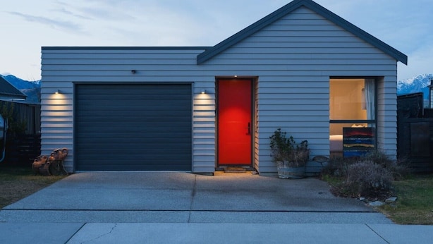 A single-story house with a garage and a red door.