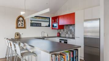 A modern kitchen with a central island, stainless steel appliances, and a red backsplash.