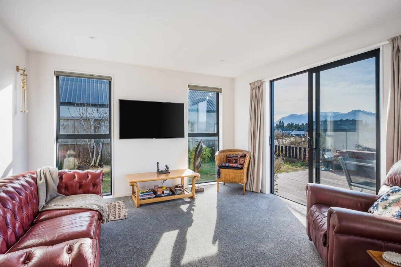 Een moderne woonkamer met een leren bank, een houten salontafel en een groot raam met uitzicht op bergen.