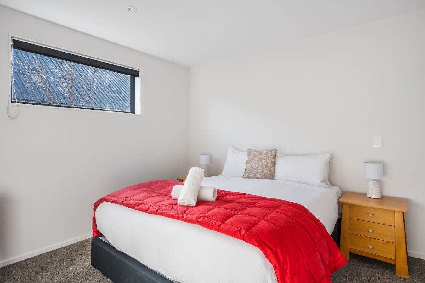 Une chambre d’hôtel avec un lit, une table de chevet, une fenêtre donnant sur un paysage agréable et un interrupteur fixé au mur.