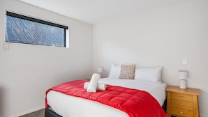 Hotellihuone, jossa on sänky, yöpöytä, ikkunasta avautuva näkymä ja seinään asennettu valokytkin.