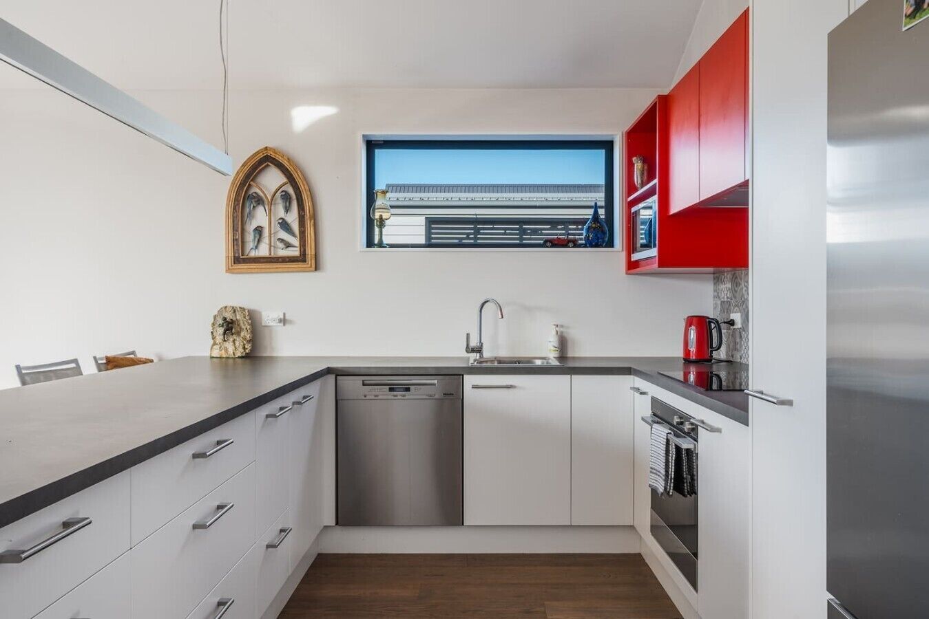 A modern kitchen with a dishwasher, sink, and red cabinets.