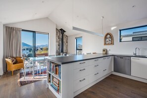 A modern kitchen with a central island, white cabinetry, and a view of the outdoors. - 3BR Wanaka Home Walkable Location Alpine Views (Wānaka)
