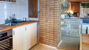 A kitchen with a wooden countertop, white cabinets, a brick wall, and a dining area with white chairs. - Stunning home in Tranås with lake view (Tranås)
