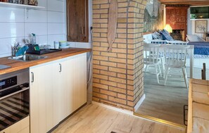 A kitchen with a wooden countertop, white cabinets, a brick wall, and a dining area with white chairs. - Stunning home in Tranås with lake view (Tranås)