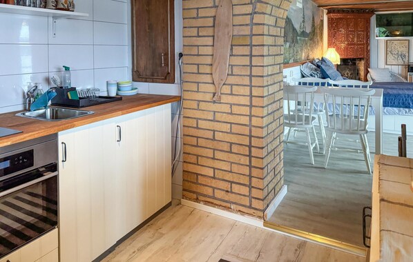 A kitchen with a wooden countertop, white cabinets, a brick wall, and a dining area with white chairs. - Stunning home in Tranås with lake view (Tranås)