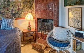 A cozy room with a fireplace, a map on the wall, and a wicker chair. - Stunning home in Tranås with lake view (Tranås)