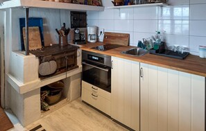 Ett kompakt kök med en inbyggd ugn, en kaffebryggare och ett handfat.
