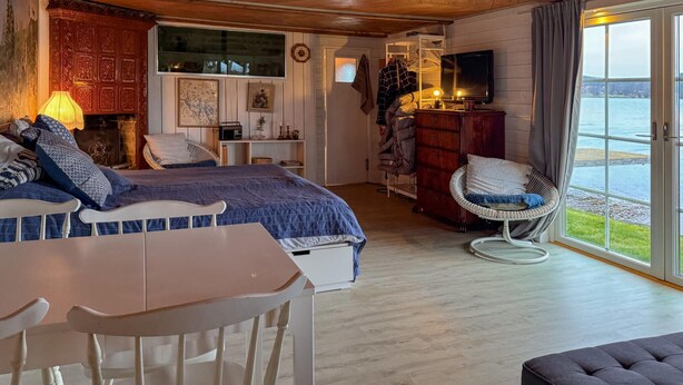 A bedroom with a bed, a chair, a table, a television, and a view of the outdoors. - Stunning home in Tranås with lake view (Tranås)