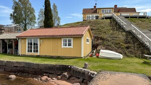 A coastal property with a yellow building, a boat, and a staircase leading to a second structure. - Stunning home in Tranås with lake view (Tranås)