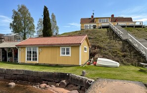 A coastal property with a yellow building, a boat, and a staircase leading to a second structure. - Stunning home in Tranås with lake view (Tranås)