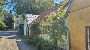 A cobblestone street with buildings on either side, one with a tiled roof and ivy-covered walls. - Stunning home in Visby with WiFi (Visby)