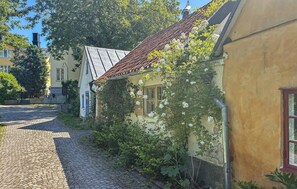 Eine Kopfsteinpflasterstraße mit Gebäuden an beiden Seiten, eines mit einem Ziegeldach und einer mit Efeu bewachsenen Fassade.