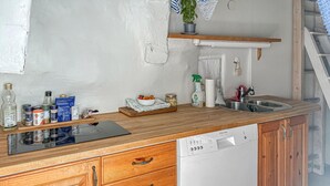 A kitchen with wooden cabinets, a dishwasher, a sink, and various kitchen items on the countertop. - Stunning home in Visby with WiFi (Visby)