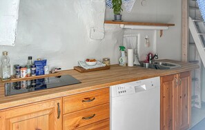 Eine Küche mit Holzschränken, einem Geschirrspüler, einem Spülbecken und verschiedenen Küchenutensilien auf der Arbeitsplatte.