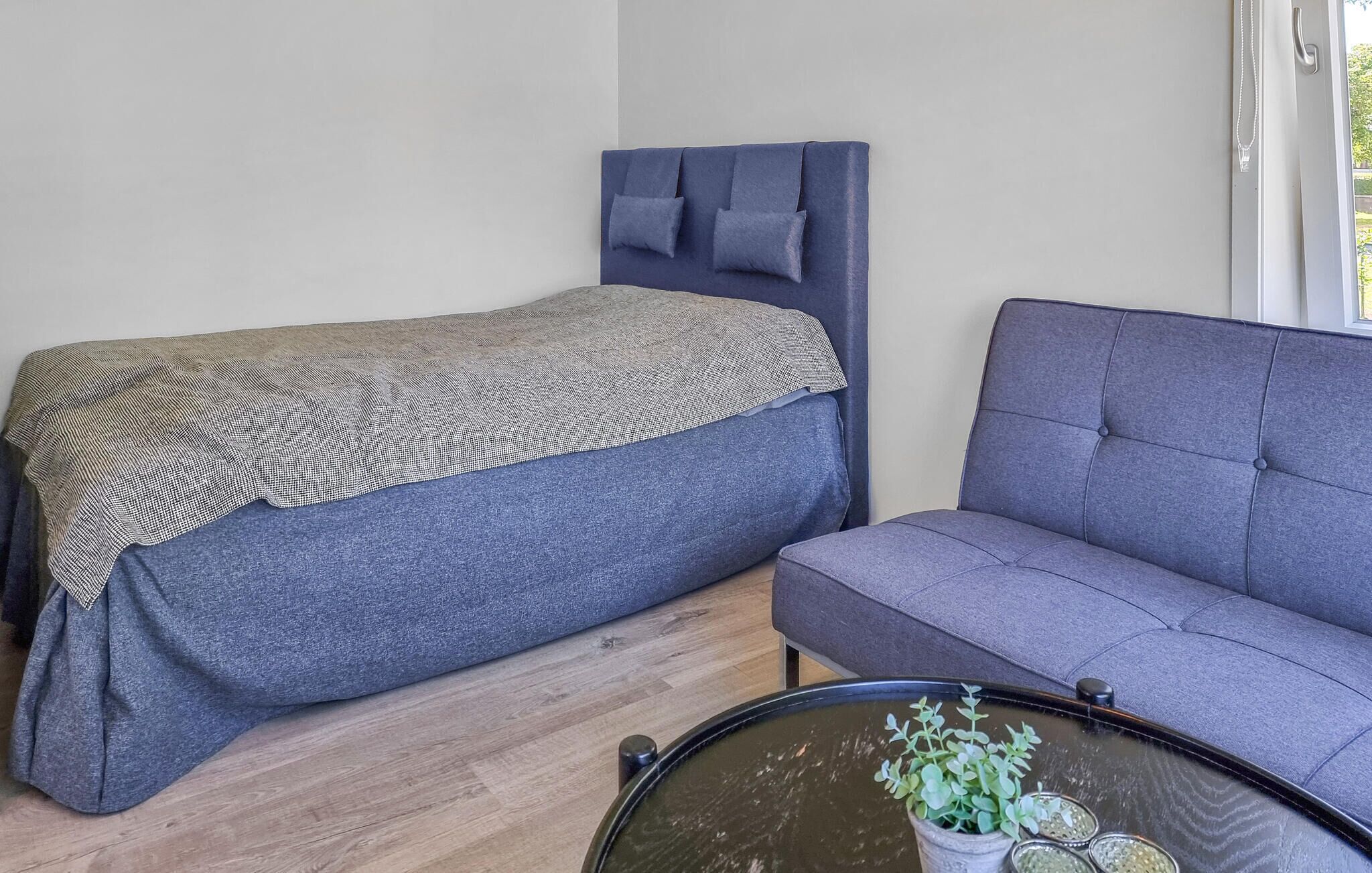 Ein Schlafzimmer mit einem Bett, einem Sofa und einem kleinen Tisch mit einer Pflanze.