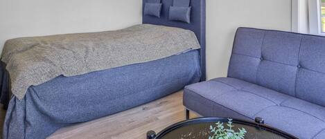 Ein Schlafzimmer mit einem Bett, einem Sofa und einem kleinen Tisch mit einer Pflanze.