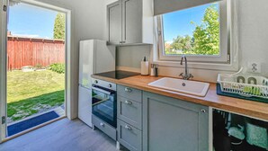 Een kleine keuken met een ingebouwde oven, een spoelbak en een raam met uitzicht op een tuin.