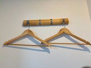Two wooden hangers on a textured wall.